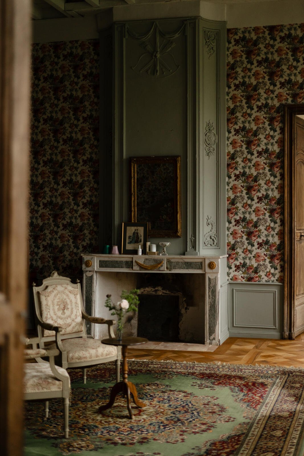 A fireplace and old wallpaper in one of the rooms