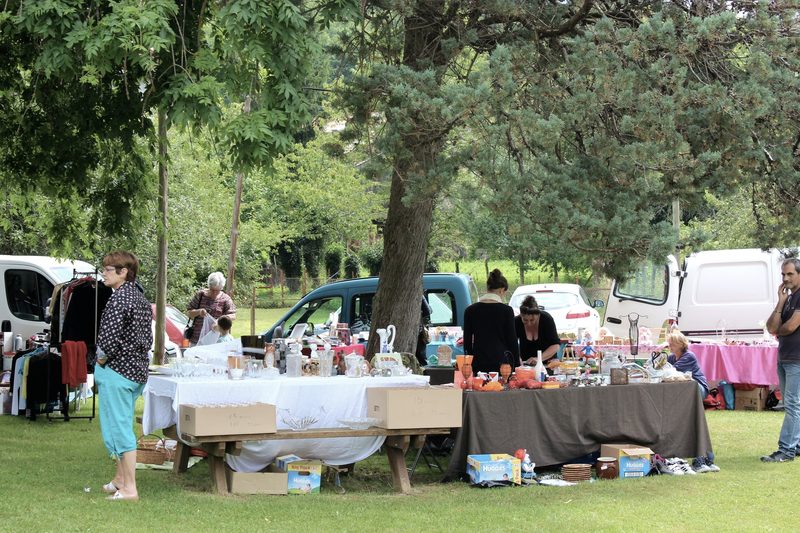 A vide-grenier on the green, people browsing