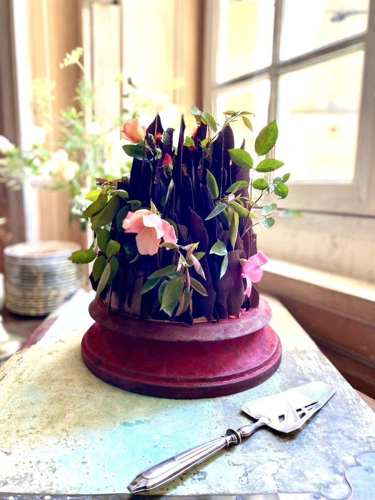 A cake dressed with dark flowers